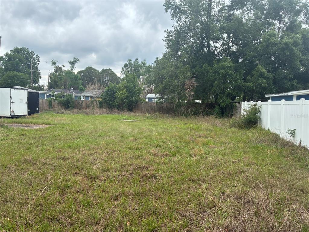 An empty, grassy residential lot features a white vinyl fence and a parked trailer — 2726 S BROWN AVENUE, ORLANDO, FL
