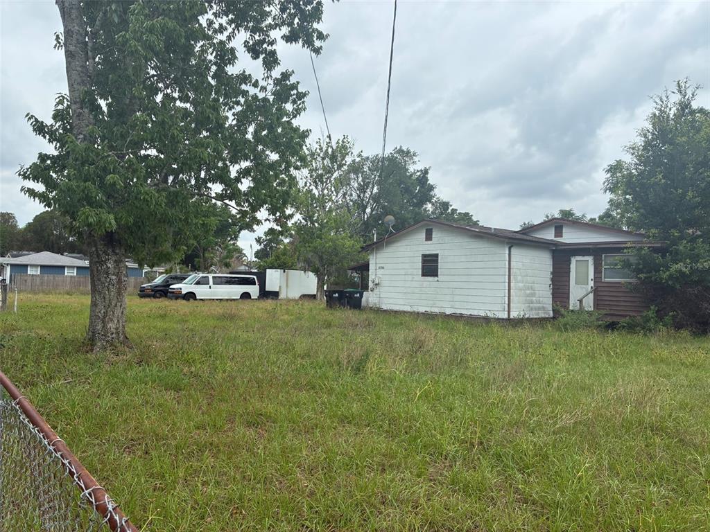 A single-story house with white siding stands on a large, grassy lot with trees — 2726 S BROWN AVENUE, ORLANDO, FL