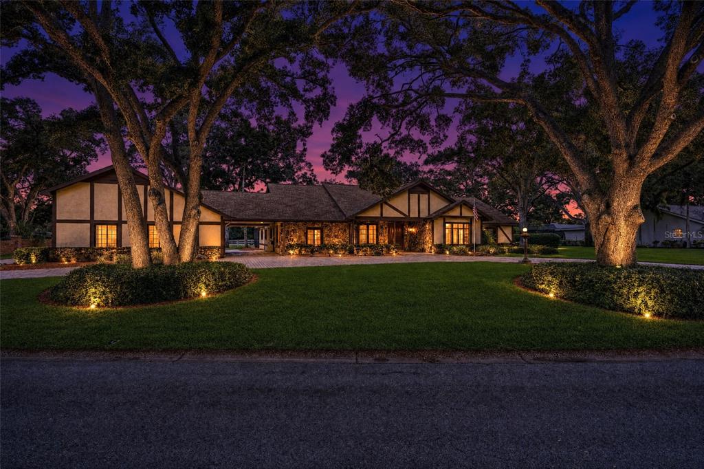 A single-story house with stone and timber framing sits behind a lawn with large trees — 2160 LAURENCE DRIVE, CLEARWATER, FL