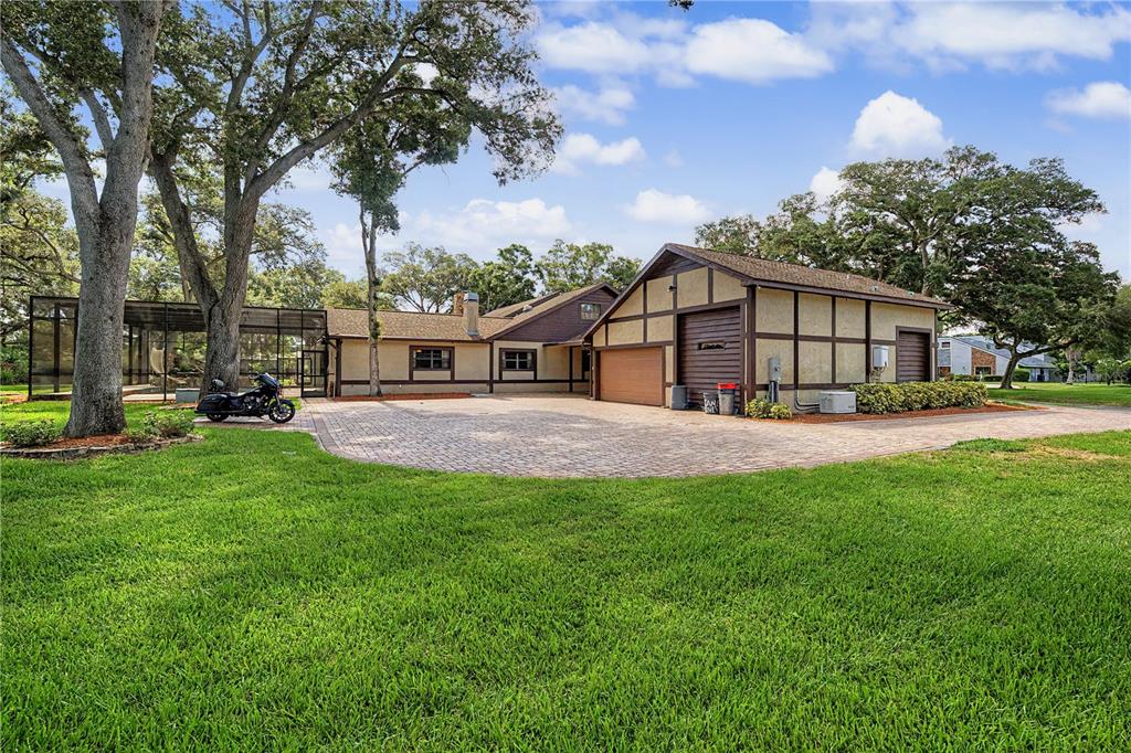 A large house with a paved driveway, a detached garage, and a screened-in patio area — 2160 LAURENCE DRIVE, CLEARWATER, FL