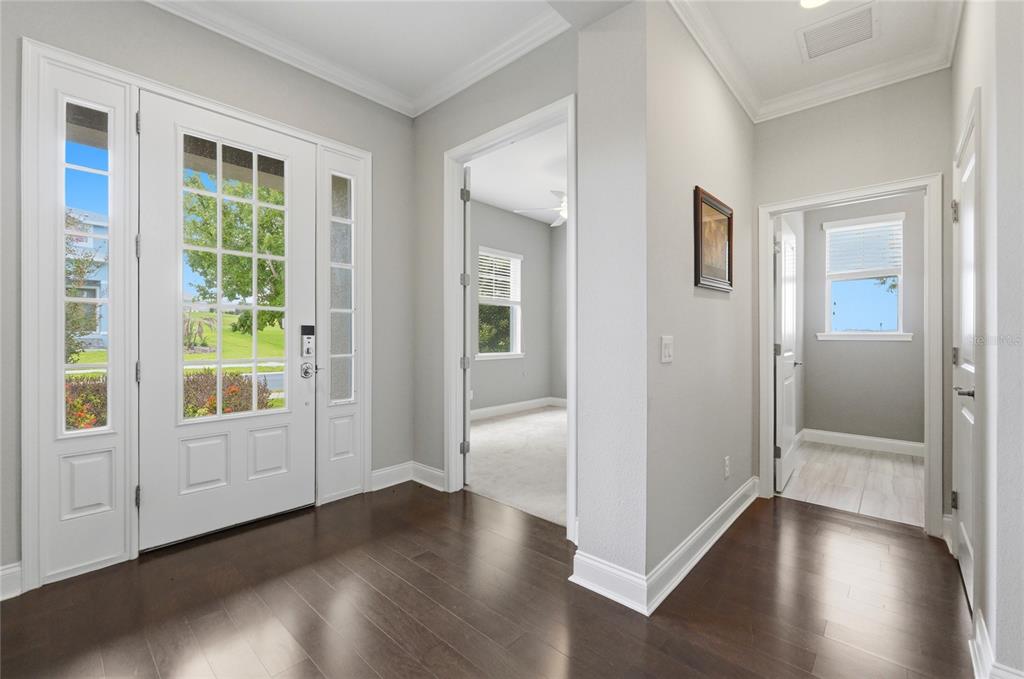 A bright entryway features dark hardwood floors, a white front door, and two interior doorways — 539 WATERFERN TRAIL DRIVE, AUBURNDALE, FL