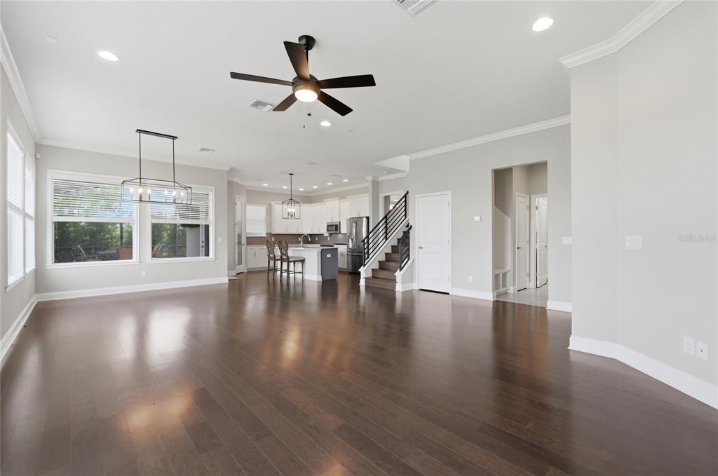 An open-concept living area features dark hardwood floors, a kitchen with an island, and stairs — 539 WATERFERN TRAIL DRIVE, AUBURNDALE, FL