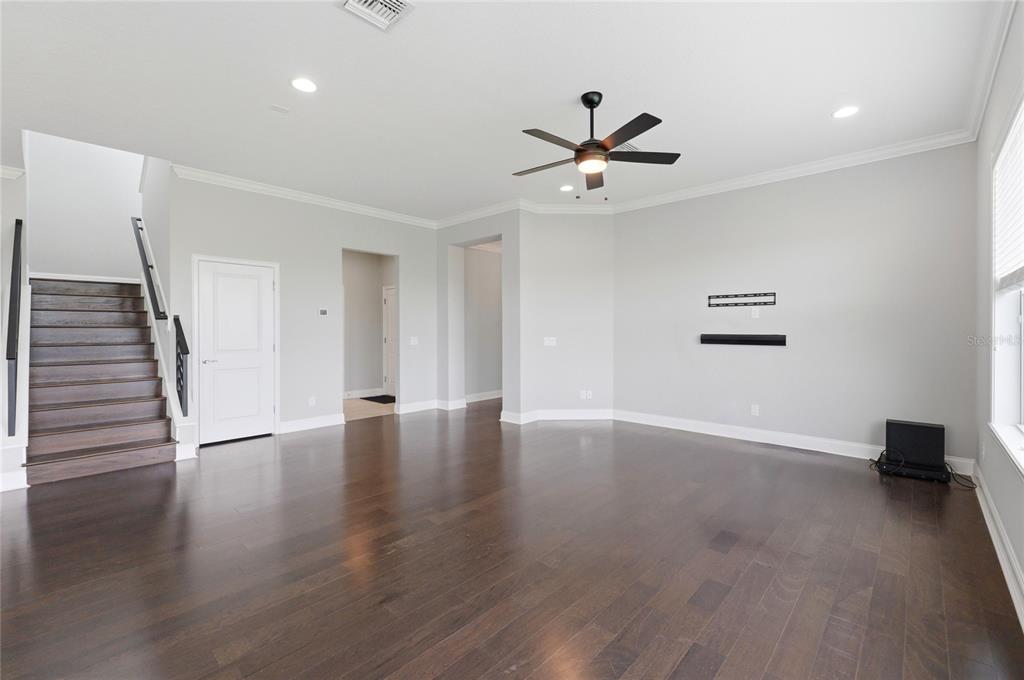 A living room with dark hardwood floors, a staircase, and a ceiling fan — 539 WATERFERN TRAIL DRIVE, AUBURNDALE, FL