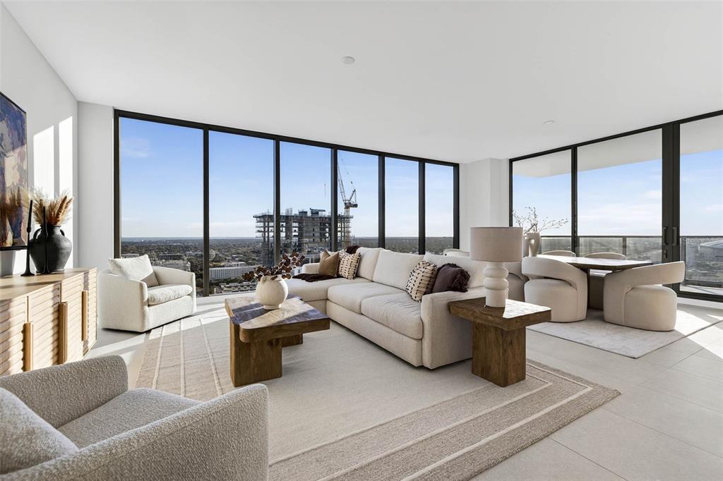 A modern living room with floor-to-ceiling windows, neutral furniture, and a view of construction — 275 1ST AVE S UNIT 2706, ST PETERSBURG, FL