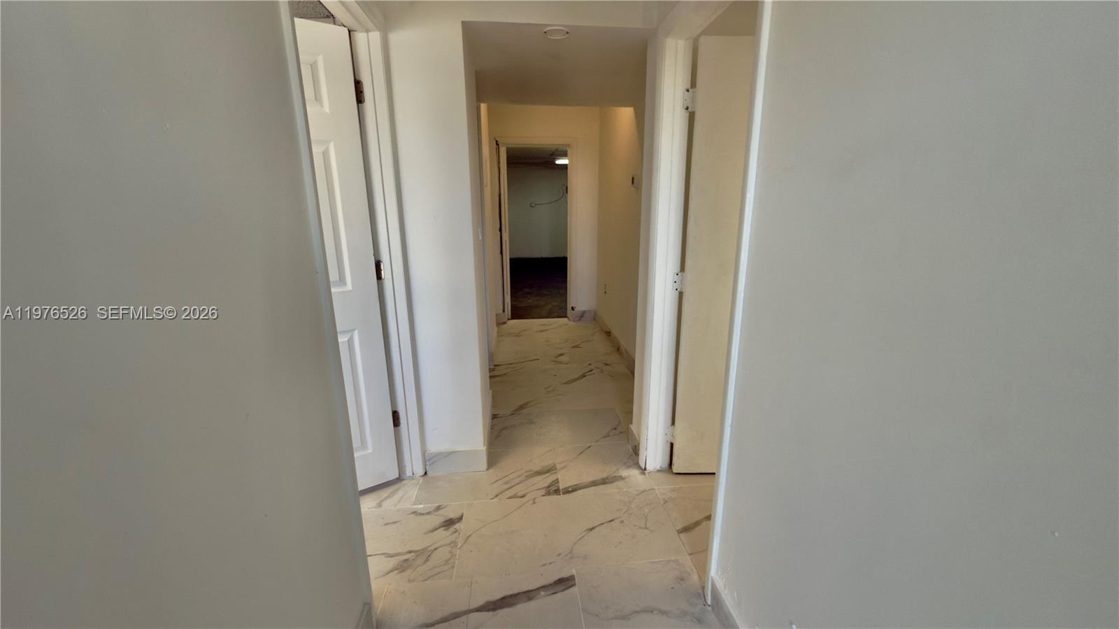 A hallway with white marble-patterned tile flooring leads to a doorway in the distance — 500 NE 25th St # 1, Pompano Beach FL 33064, POMPANO BEACH, FL