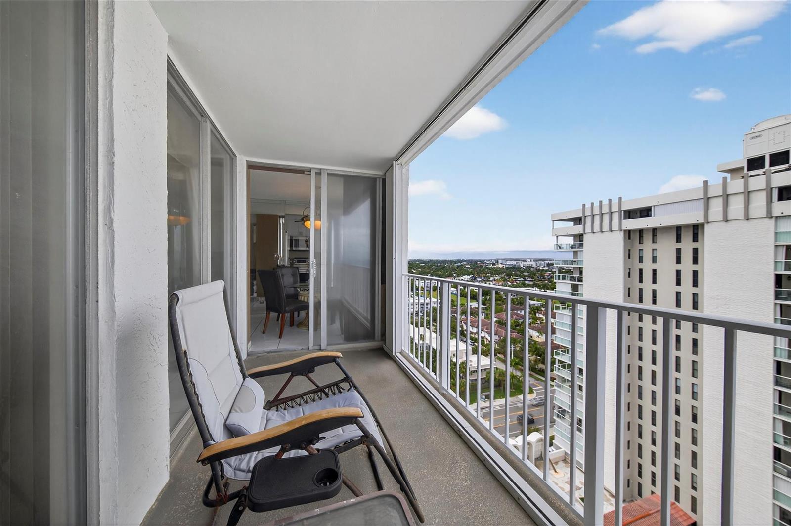 A balcony with a lounge chair overlooks a city view and a neighboring high-rise building — 1010 S Ocean Boulevard # 1711, Pompano Beach FL 33062, POMPANO BEACH, FL