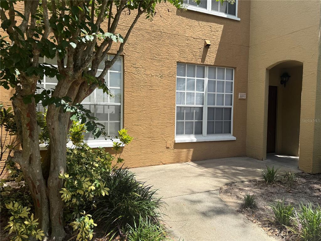 A tan stucco building exterior features a concrete walkway leading to a recessed front entrance — 6384 RALEIGH STREET UNIT 2203, ORLANDO, FL