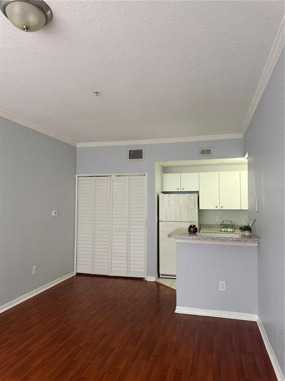 An interior view shows a room with wood-look flooring, a white closet, and a kitchen — 6384 RALEIGH STREET UNIT 2203, ORLANDO, FL