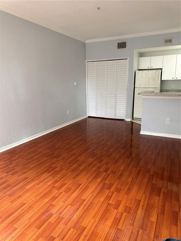 A kitchen with white cabinets and a breakfast bar opens into a room with wood floors — 6384 RALEIGH STREET UNIT 2203, ORLANDO, FL