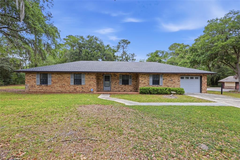 A single-story brick house with a gray roof, attached garage, and a large front lawn — 4803 W STATE ROAD 238, LAKE BUTLER, FL