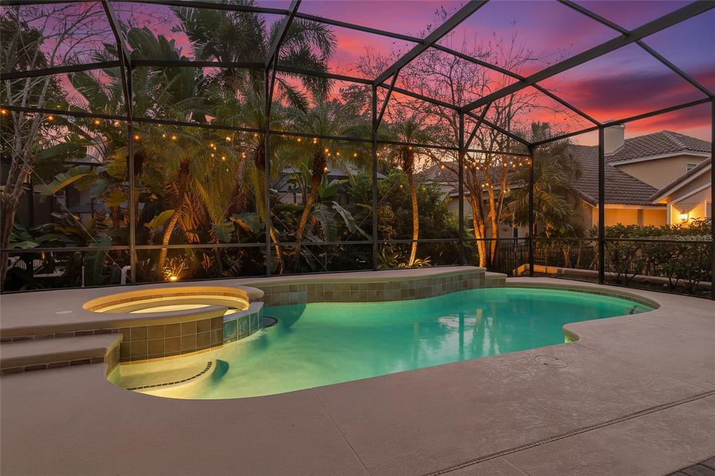 A swimming pool and attached spa are enclosed within a screened lanai at sunset — 6976 LUCCA STREET, ORLANDO, FL