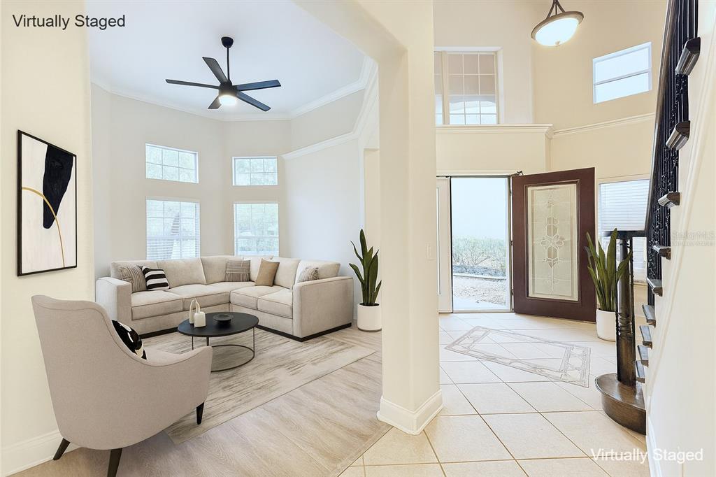 A living room with a sectional sofa and an adjacent tiled entryway with a staircase — 6976 LUCCA STREET, ORLANDO, FL