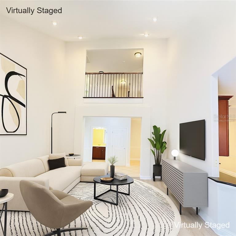 A living room with high ceilings, a loft overlook, and modern furniture on a circular rug — 6976 LUCCA STREET, ORLANDO, FL