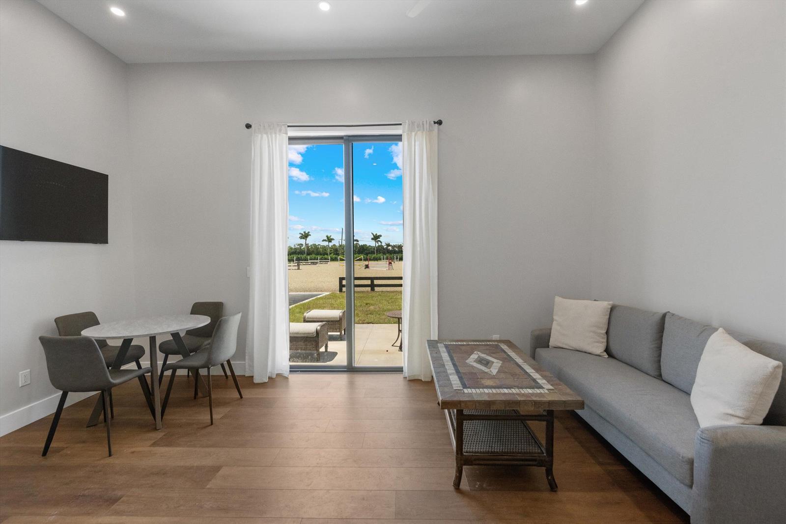 A living and dining room features wood-look flooring, a gray sofa, and a sliding glass door — 16175 Deer Path Lane, Wellington FL 33470, WELLINGTON, FL