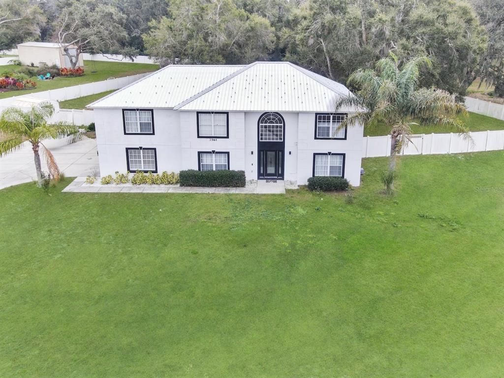An aerial view of a two-story white house with a metal roof and black trim — 7561 LAKE ANDREA CIRCLE, MOUNT DORA, FL