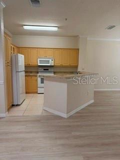 A kitchen features light wood cabinets, stainless steel appliances, and a central island — 3707 CONROY ROAD UNIT 1713, ORLANDO, FL