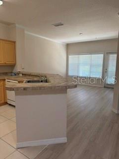A kitchen with light wood cabinets and a breakfast bar overlooks a living area — 3707 CONROY ROAD UNIT 1713, ORLANDO, FL