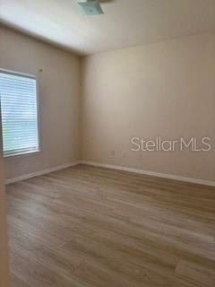 An empty bedroom features light-colored wood-look flooring, beige walls, and a window with blinds — 3707 CONROY ROAD UNIT 1713, ORLANDO, FL