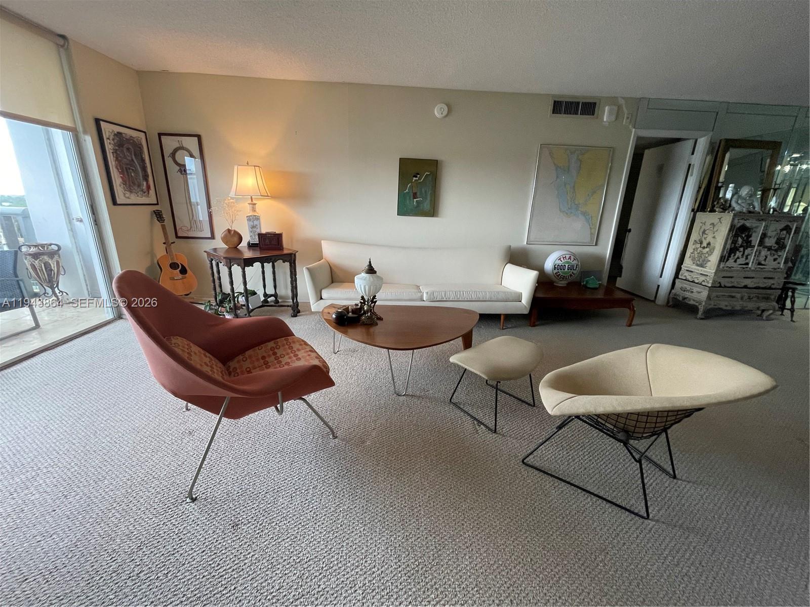 A living room features mid-century modern furniture, a white sofa, and a large sliding glass door — 6039 Collins Ave # 1232, Miami Beach FL 33140, MIAMI BEACH, FL
