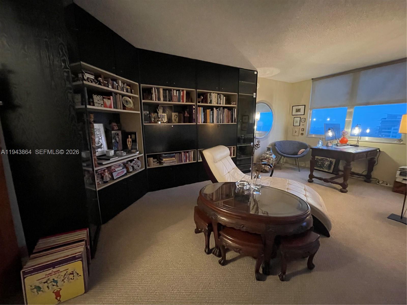 A home office features built-in black shelving, a chaise lounge, and a wooden desk — 6039 Collins Ave # 1232, Miami Beach FL 33140, MIAMI BEACH, FL