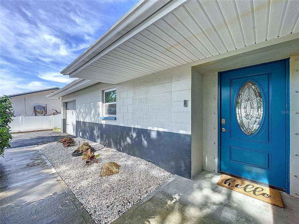 A blue front door with a decorative glass insert sits beside a white block wall — 7960 2ND STREET N, ST PETERSBURG, FL