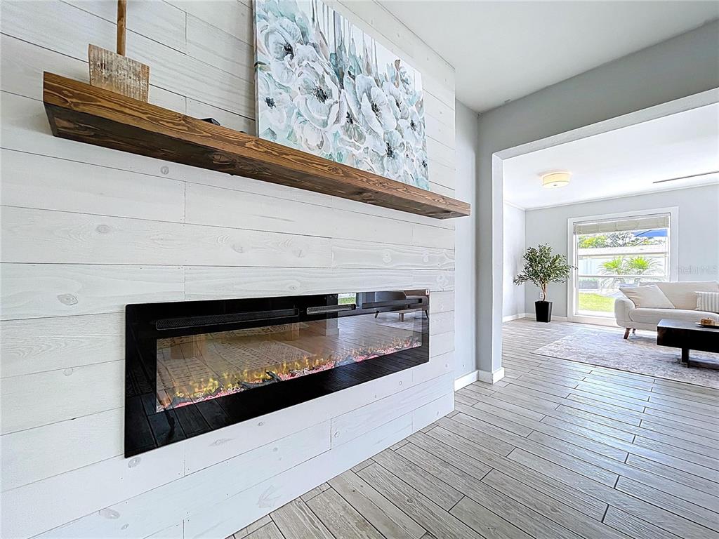 A living room features a white shiplap wall with a fireplace and wooden mantel — 7960 2ND STREET N, ST PETERSBURG, FL