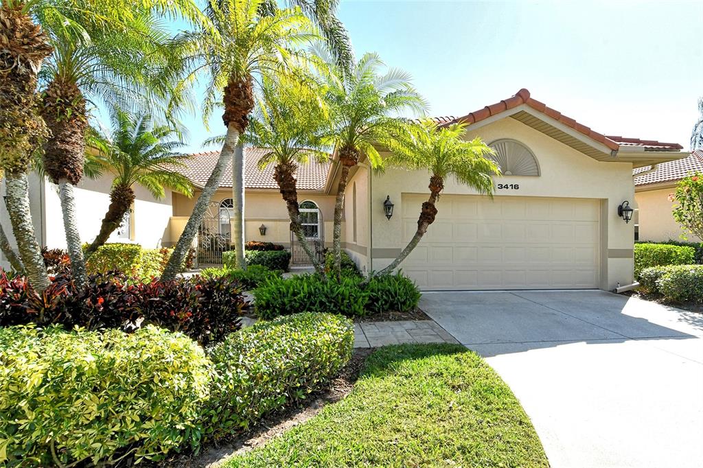 A single-story house with a beige stucco exterior, a tiled roof, and a two-car garage — 3416 W CHELMSFORD COURT UNIT 2, SARASOTA, FL