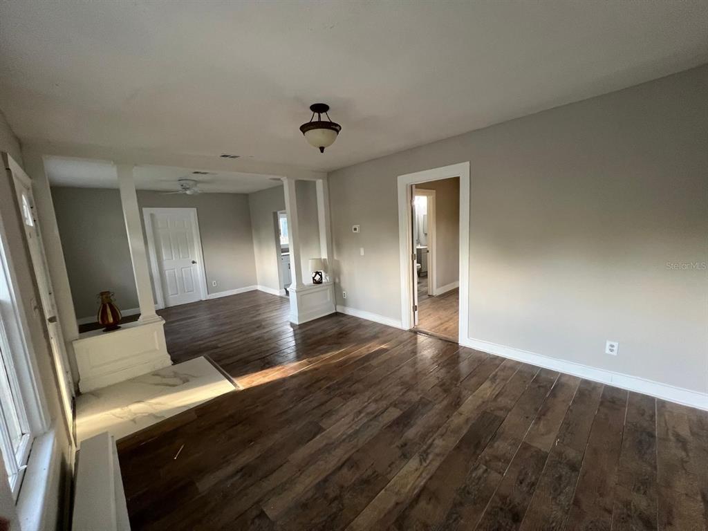 A living room with dark wood-look flooring, light gray walls, and a white column divider — 8210 N 13TH STREET, TAMPA, FL