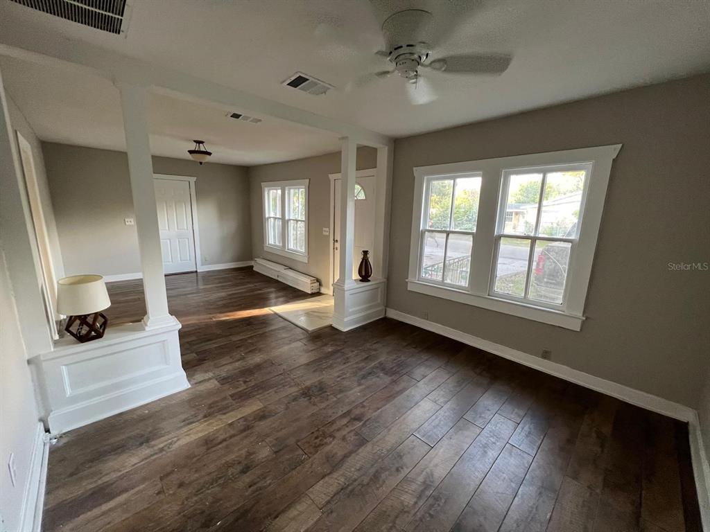 A living room with wood-look flooring, white columns, and large windows — 8210 N 13TH STREET, TAMPA, FL