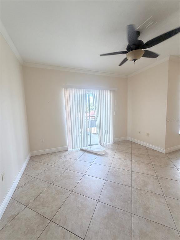An empty room features beige tile flooring, a ceiling fan, and sliding glass balcony doors — 5525 PGA BOULEVARD SW UNIT 4625, ORLANDO, FL