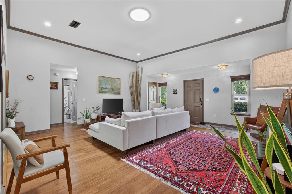 A living room features a white sectional sofa, a large red rug, and wood flooring — 2840 NW 27TH TERRACE, GAINESVILLE, FL
