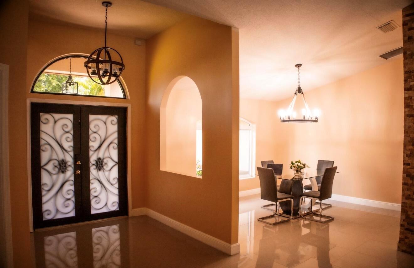A foyer with a decorative front door leads into a dining room with a chandelier — 12288 82nd Lane N, FL 33412, FL