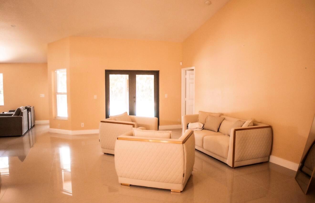 A living room with light-colored tile floors, peach walls, and a matching furniture set — 12288 82nd Lane N, FL 33412, FL