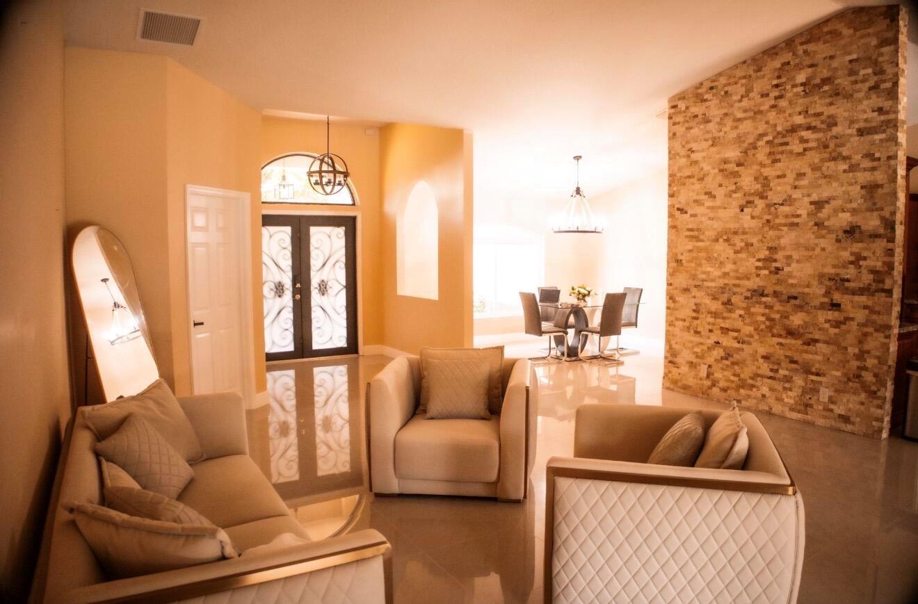 A living room with beige furniture, a stone accent wall, and a formal dining area — 12288 82nd Lane N, FL 33412, FL