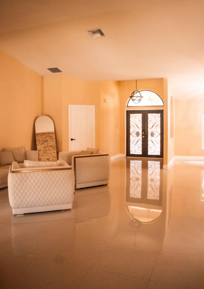 A living room features light-colored tile floors, peach walls, and a decorative glass front door — 12288 82nd Lane N, FL 33412, FL