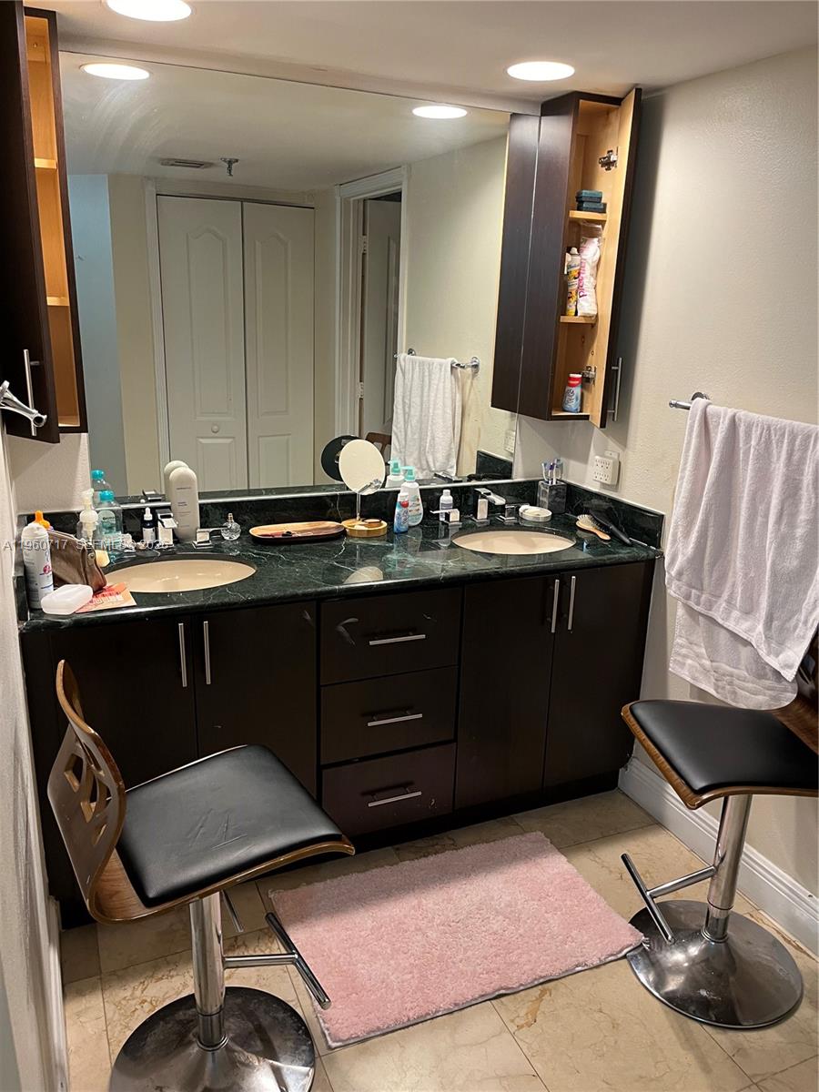 A bathroom features a double-sink vanity with dark cabinets, green countertops, and two stools — 520 Brickell Key Dr # A610, Miami FL 33131, MIAMI, FL