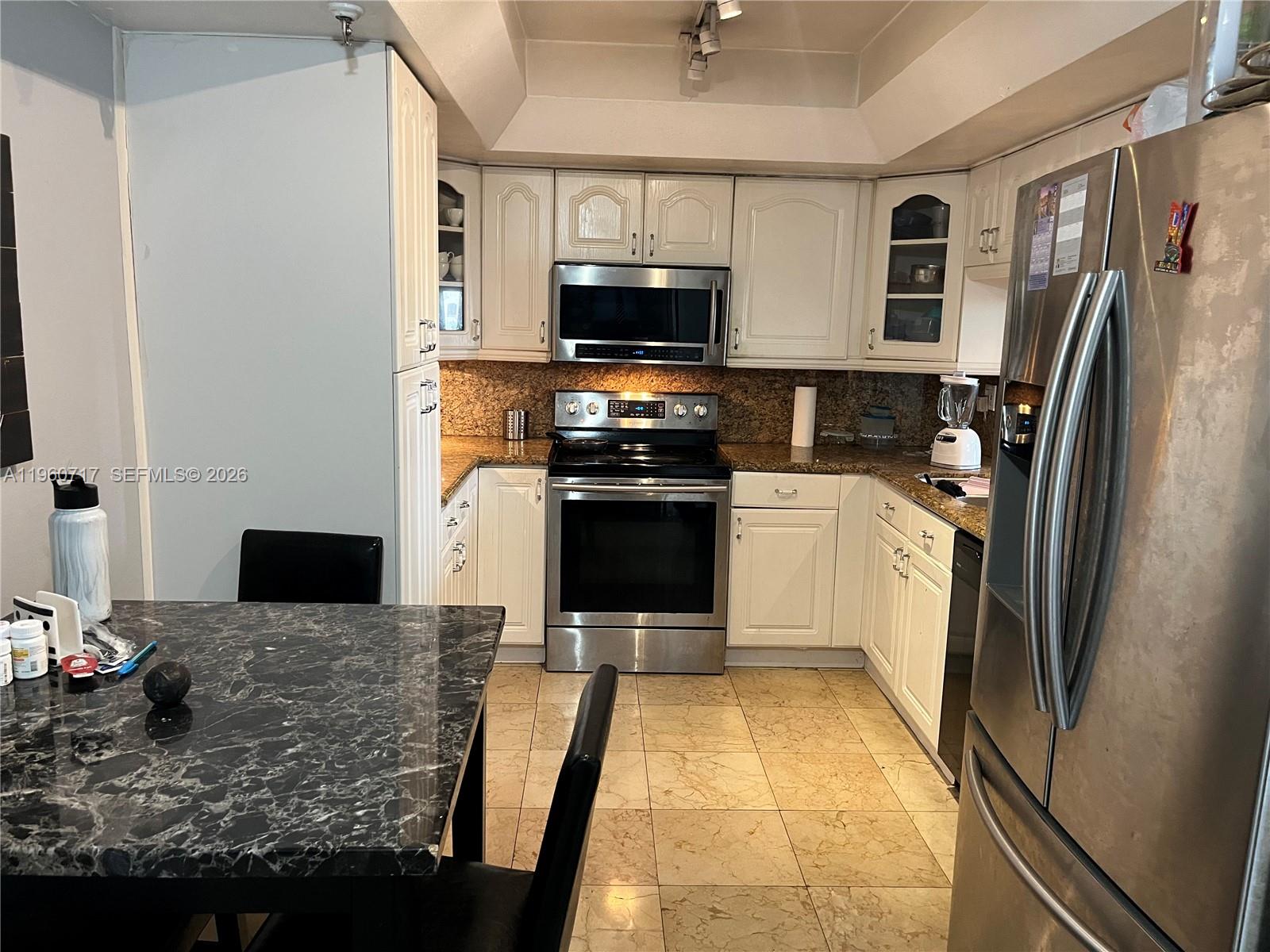A kitchen features white cabinets, stainless steel appliances, and granite countertops with tile flooring — 520 Brickell Key Dr # A610, Miami FL 33131, MIAMI, FL
