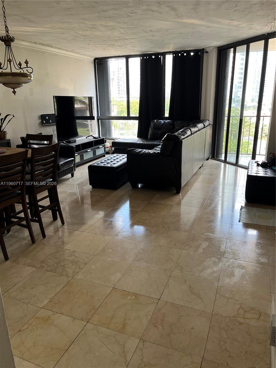 A living and dining area features tile flooring, a black sectional sofa, and floor-to-ceiling windows — 520 Brickell Key Dr # A610, Miami FL 33131, MIAMI, FL