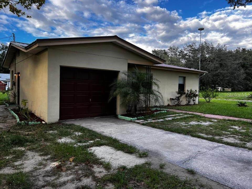 A single-story house with a tan exterior, a one-car garage, and a concrete driveway — 331 STEEDLY AVENUE, LAKE WALES, FL