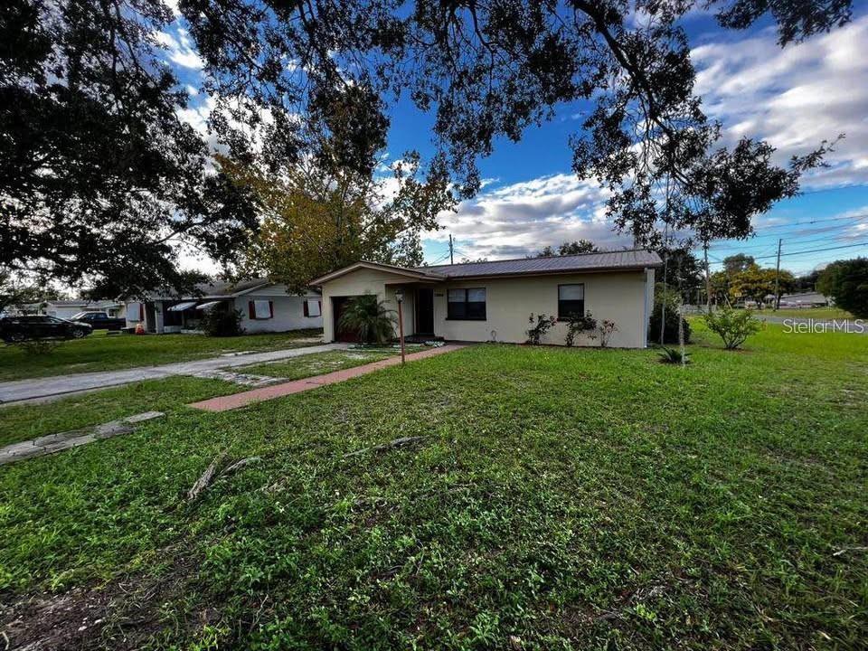 A single-story house with a tan exterior, metal roof, and a front lawn with trees — 331 STEEDLY AVENUE, LAKE WALES, FL