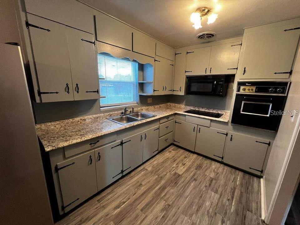 A kitchen features grey cabinets, granite countertops, stainless steel appliances, and wood-look flooring — 331 STEEDLY AVENUE, LAKE WALES, FL