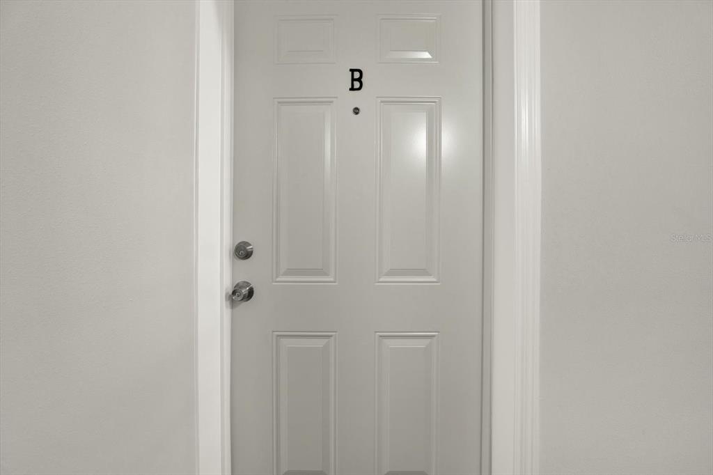A white interior door labeled with the letter B features a peephole and hardware — 8345 13TH STREET N UNIT B, ST PETERSBURG, FL