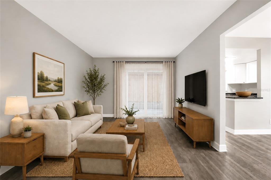 An empty living room features gray wood-look flooring, light walls, and a sliding glass door — 8345 13TH STREET N UNIT B, ST PETERSBURG, FL