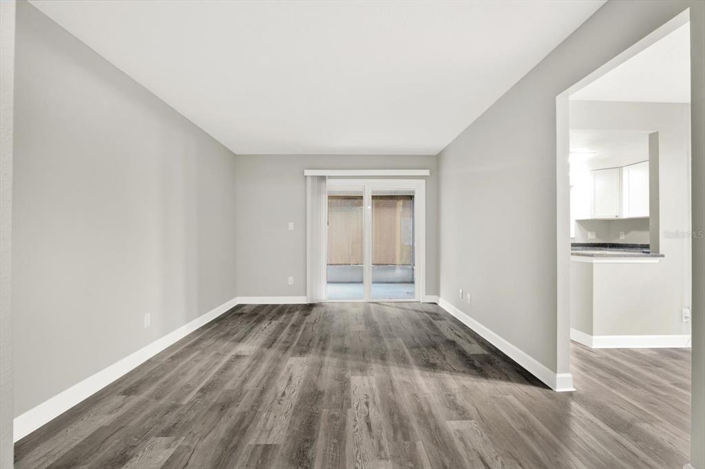 An interior view shows a living area with gray wood-look flooring and a sliding door — 8345 13TH STREET N UNIT B, ST PETERSBURG, FL