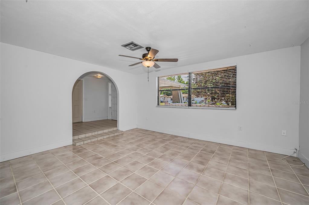 A room with white walls, tiled floors, an arched doorway, and a ceiling fan — 5817 10TH AVENUE, NEW PORT RICHEY, FL