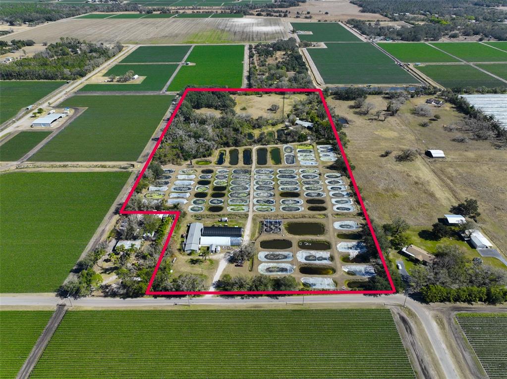 Aerial view of a rural property featuring numerous small ponds and agricultural buildings — 20112 HOBBS ROAD, WIMAUMA, FL
