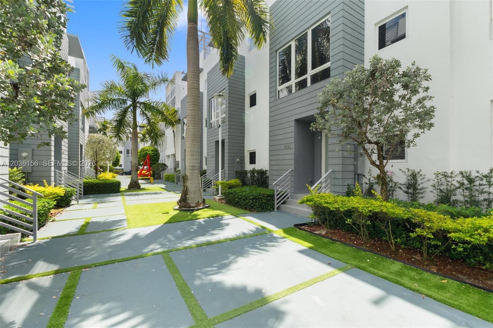 A modern multi-story townhouse exterior with gray siding, white walls, and a landscaped walkway — 9161 NW 33rd St # 0, Doral FL 33172, DORAL, FL