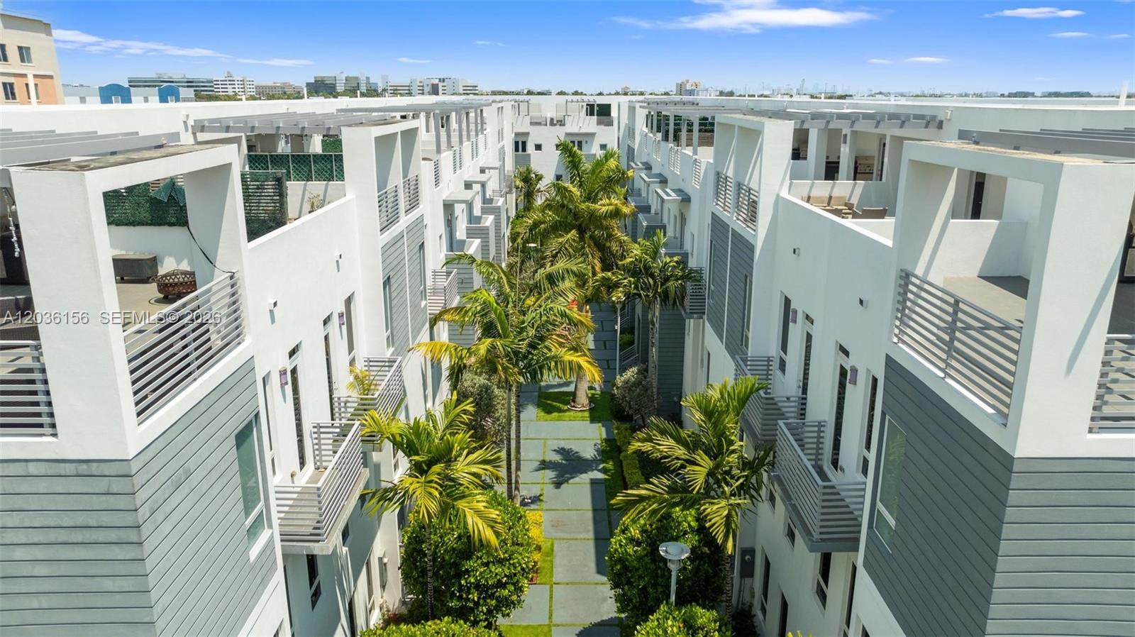 An aerial view shows a narrow courtyard between two modern white multi-story townhome buildings — 9161 NW 33rd St # 0, Doral FL 33172, DORAL, FL