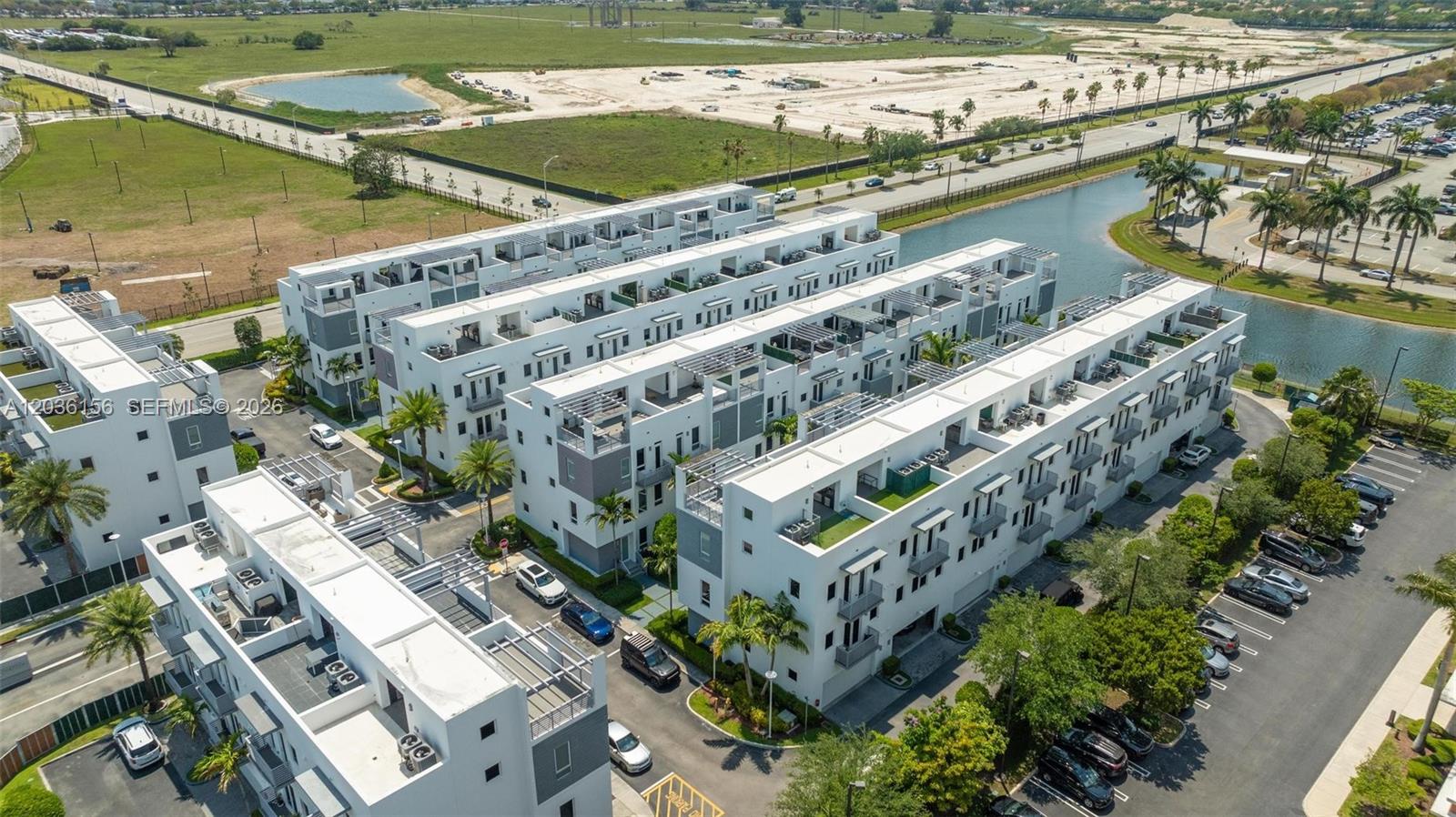 An aerial view shows multiple modern white townhome buildings with rooftop terraces and parking areas — 9161 NW 33rd St # 0, Doral FL 33172, DORAL, FL