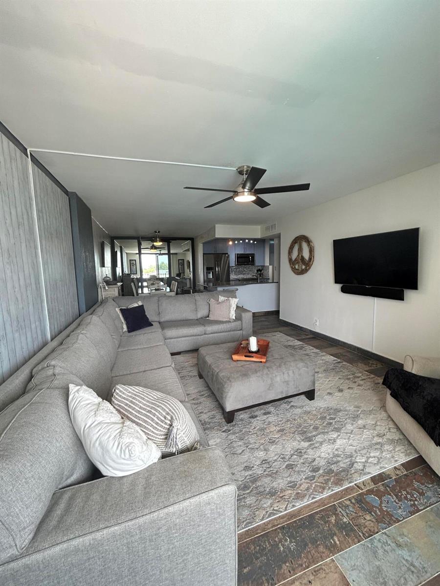 A living room features a large gray sectional sofa, a matching ottoman, and a wall-mounted television — 1009 N Ocean Boulevard N # 401, Pompano Beach FL 33062, POMPANO BEACH, FL